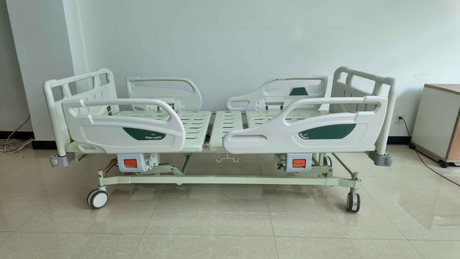 Side view of a three-function manual hospital bed with green headboard.jpg