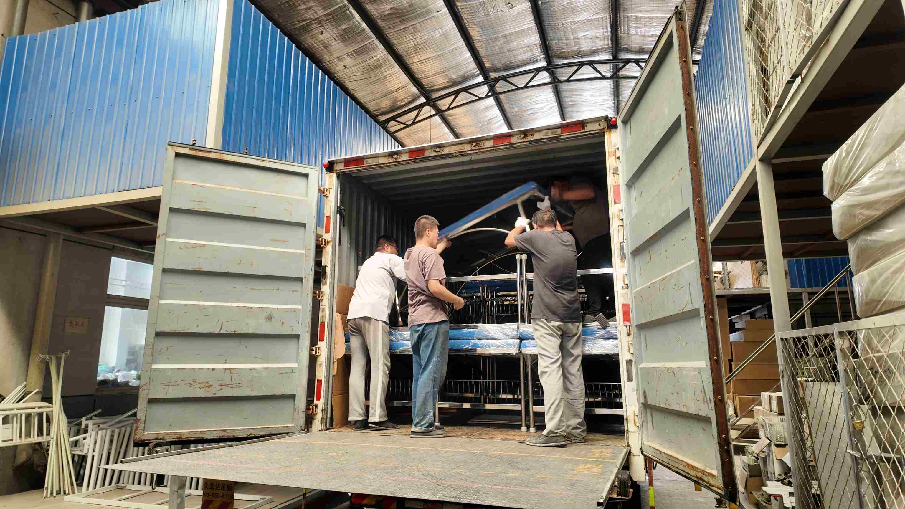 Workers are transporting and loading the examination beds into the vehicle.